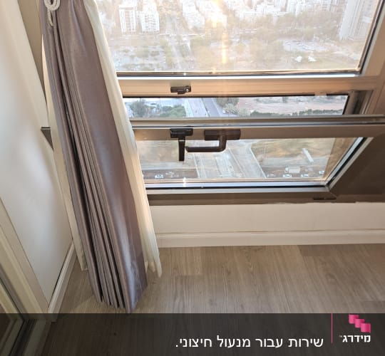 חלון עם תריסים ונוף עירוני מבחוץ